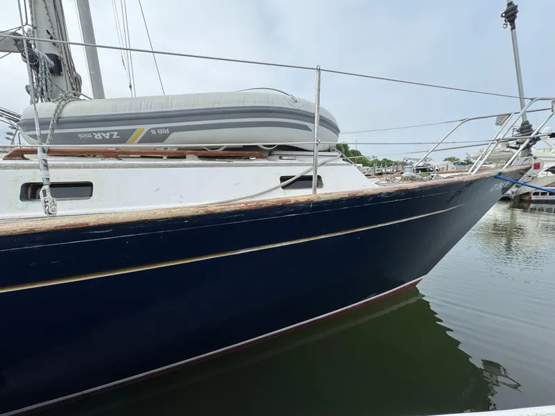 Slide: The Image of 1982 Passport 40 sailboat with dinghy, docked in calm waters. - 2