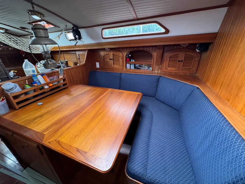 Slide: The Image of Cozy interior of 1982 Passport 40 sailboat with wooden table and blue cushioned seating. - 24