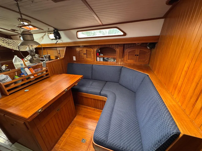 Slide: The Image of Cozy 1982 Passport 40 sailboat interior with wooden paneling and blue cushioned seating. - 25