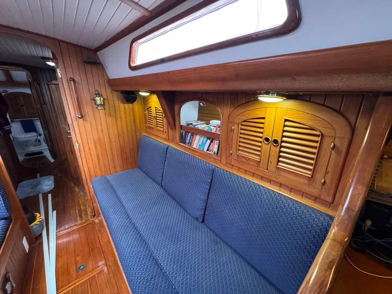 Slide: The Image of Interior of 1982 Passport 40 sailboat with wooden paneling and blue cushioned seating. - 26