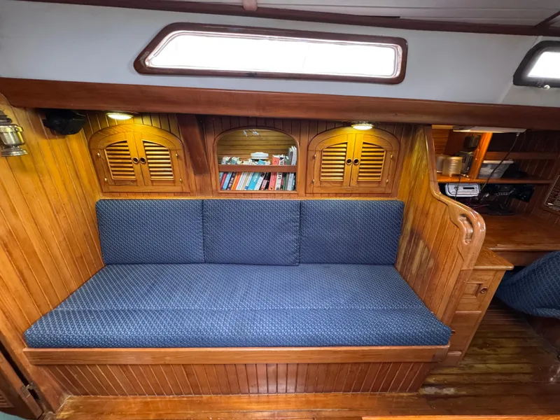 Slide: The Image of Cozy wooden interior of 1982 Passport 40 sailboat with blue cushioned seating and bookshelves. - 27