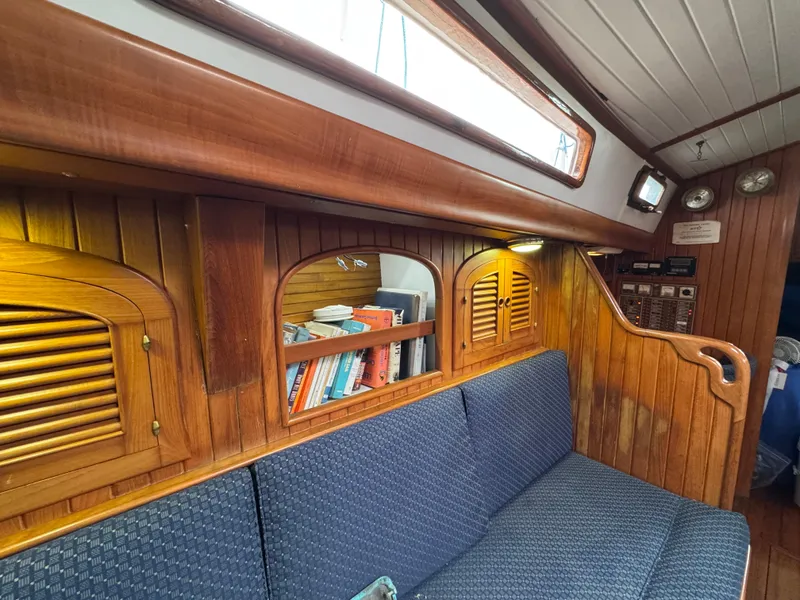 Slide: The Image of Interior of 1982 Passport 40 sailboat with wooden paneling and blue cushioned seating. - 28