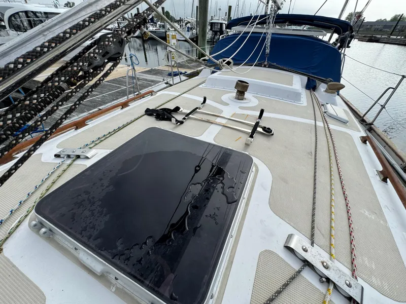 Slide: The Image of Sailboat deck of 1982 Passport 40, featuring rigging and hatch, docked at marina. - 7