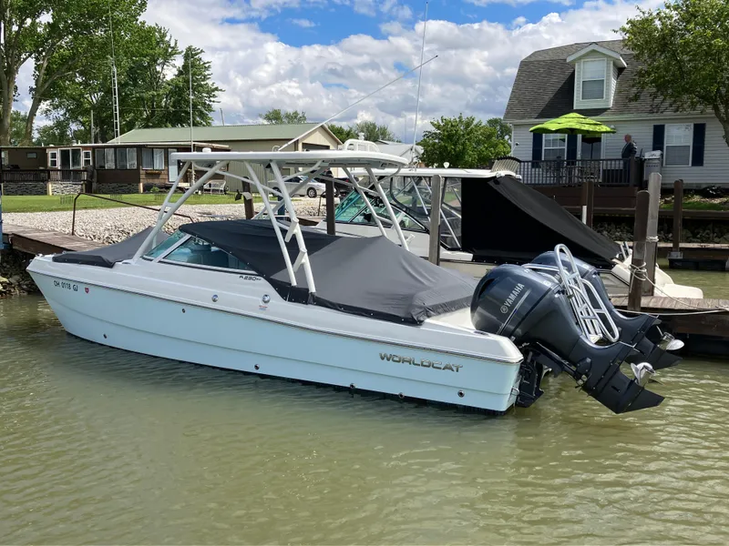 Slide: The Image of 2022 World Cat 230 SD boat docked by a lakeside house under a partly cloudy sky. - 12