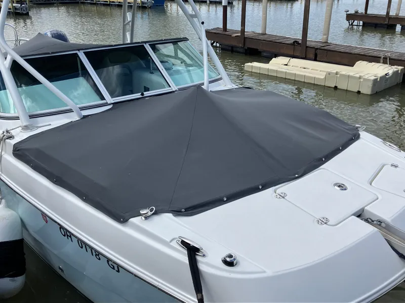 Slide: The Image of 2022 World Cat 230 SD boat with black cover docked on calm water. - 13