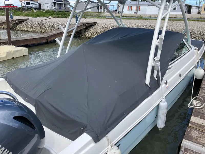 Slide: The Image of 2022 World Cat 230 SD boat with cover, docked by a rocky shoreline. - 14