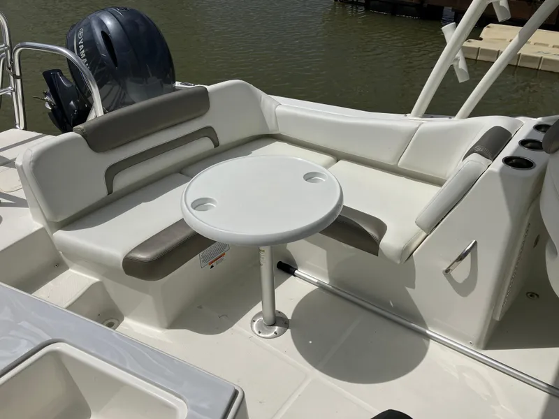 Slide: The Image of 2022 World Cat 230 SD boat interior with seating and table, docked by the water. - 19