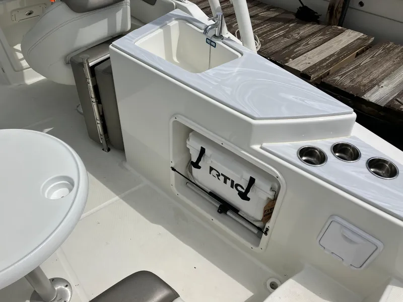 Slide: The Image of 2022 World Cat 230 SD boat interior with sink, cooler, and cup holders. - 23