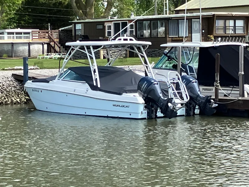 Slide: The Image of 2022 World Cat 230 SD boat docked with twin engines, near waterfront homes. - 3