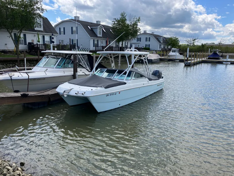 Slide: The Image of 2022 World Cat 230 SD boat docked in a serene marina setting. - 6