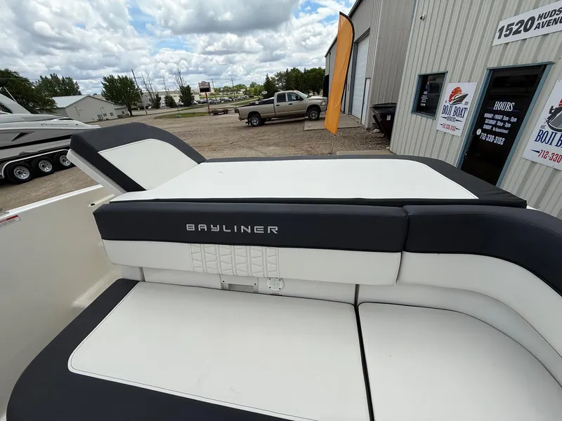Slide: The Image of 2021 Bayliner VR5 boat interior with cushioned seating, parked outside a dealership. - 19