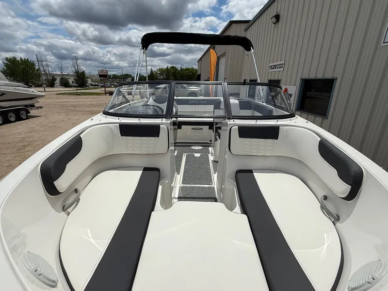 Slide: The Image of 2021 Bayliner VR5 boat interior with seating, docked near a building under cloudy skies. - 5