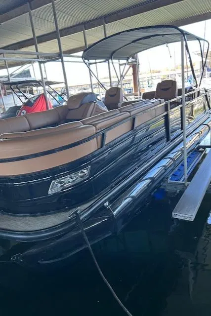 Slide: The Image of 2022 Regency 250 LE3 Sport pontoon boat docked under a covered marina. - 2