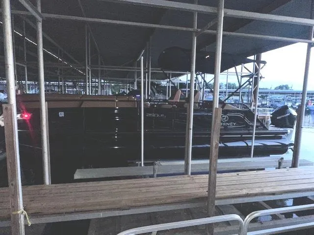 Slide: The Image of 2022 Regency 250 LE3 Sport pontoon boat docked under a covered marina. - 26