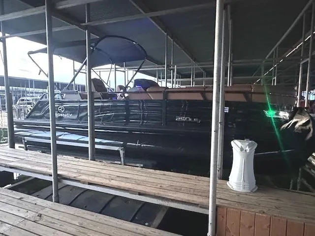 Slide: The Image of 2022 Regency 250 LE3 Sport pontoon boat docked under a covered marina. - 8