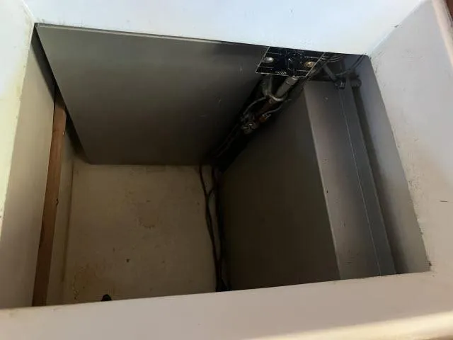 Slide: The Image of Empty compartment inside 1983 Bluewater Vagabond 47 sailboat, showing wiring and metal panel. - 12