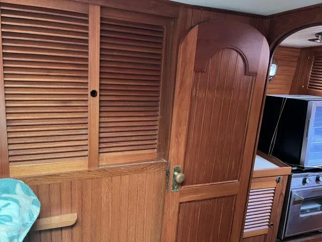 Slide: The Image of Interior of 1983 Bluewater Vagabond 47 yacht with wooden paneling and kitchen area. - 14