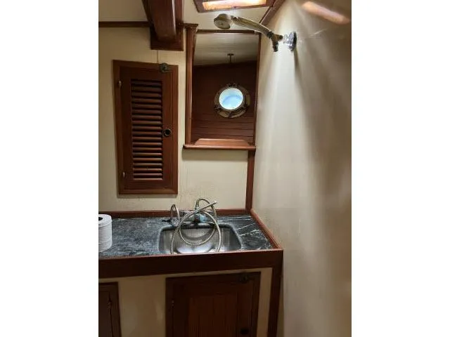 Slide: The Image of 1983 Bluewater Vagabond 47 yacht bathroom with sink, porthole, and wooden accents. - 26