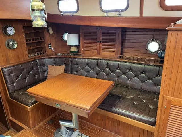 Slide: The Image of Cozy 1983 Bluewater Vagabond 47 yacht interior with leather seating and wooden table. - 3