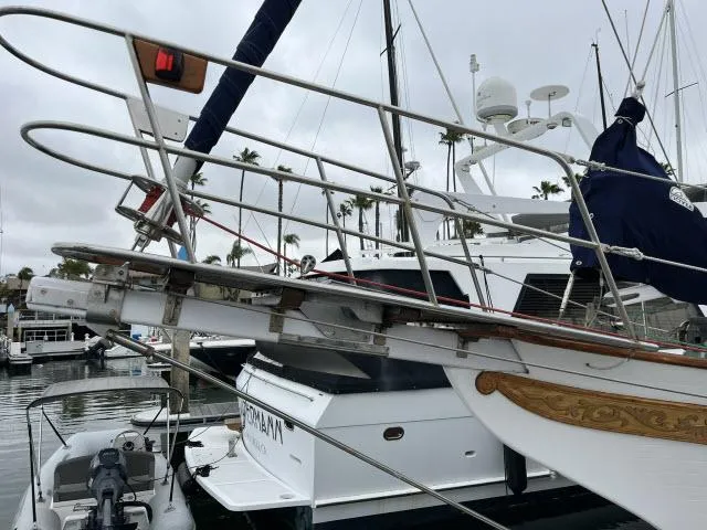 Slide: The Image of 1983 Bluewater Vagabond 47 sailboat docked in marina, featuring detailed woodwork and metal railings. - 42