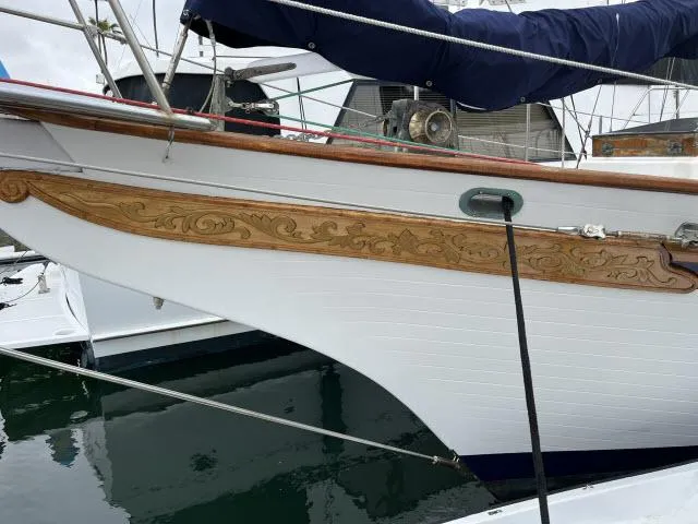 Slide: The Image of 1983 Bluewater Vagabond 47 sailboat with decorative wooden trim at a marina. - 43