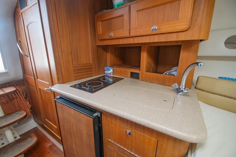 Slide: The Image of 2009 Pro-Line 35 Express boat interior with kitchenette, featuring wood cabinets and compact appliances. - 12