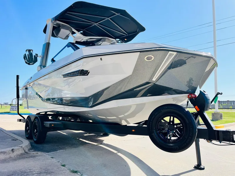 Slide: The Image of 2025 Nautique Super Air G23 boat on trailer, sleek design, sunny day. - 2
