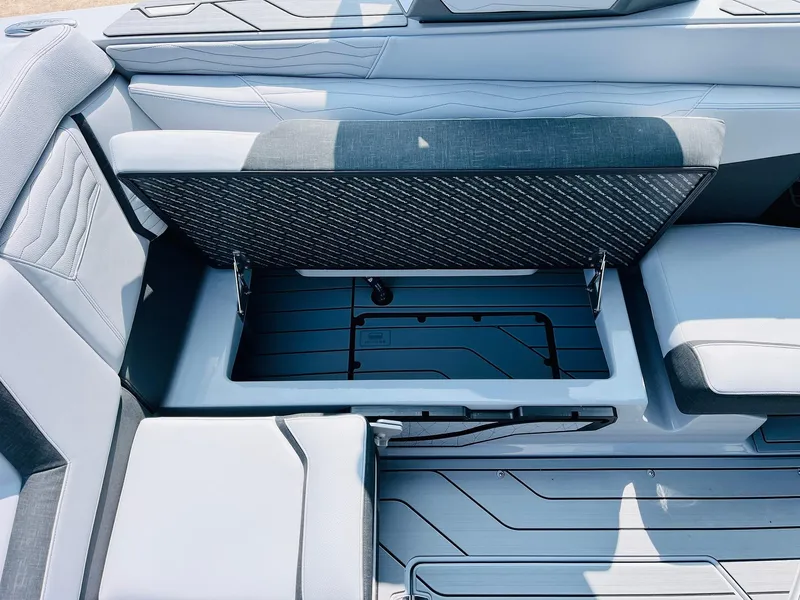 Slide: The Image of 2025 Nautique Super Air G23 boat interior with open storage compartment and sleek seating design. - 33