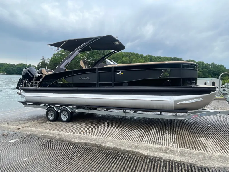 The Image of 2025 Barletta L25MAT pontoon boat on trailer by a lake. - 2