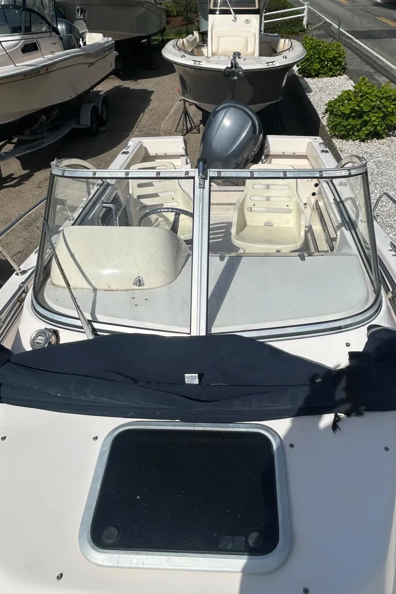 Slide: The Image of 2006 Grady-White Adventure 208 boat with windshield and outboard motor, docked outdoors. - 7
