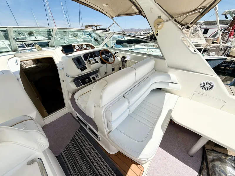 Slide: The Image of 1998 Sea Ray Sundancer 330 interior with white seating, helm, and compact kitchenette. - 6