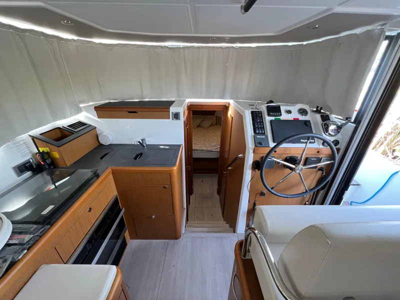 Slide: The Image of Interior of 2020 Beneteau Swift Trawler 35, featuring helm, kitchen, and cabin entrance. - 8