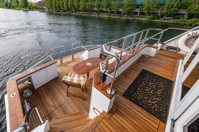 Slide: The Image of Luxurious Broward 102 yacht deck with wooden flooring, elegant seating, and scenic waterfront view. - 10