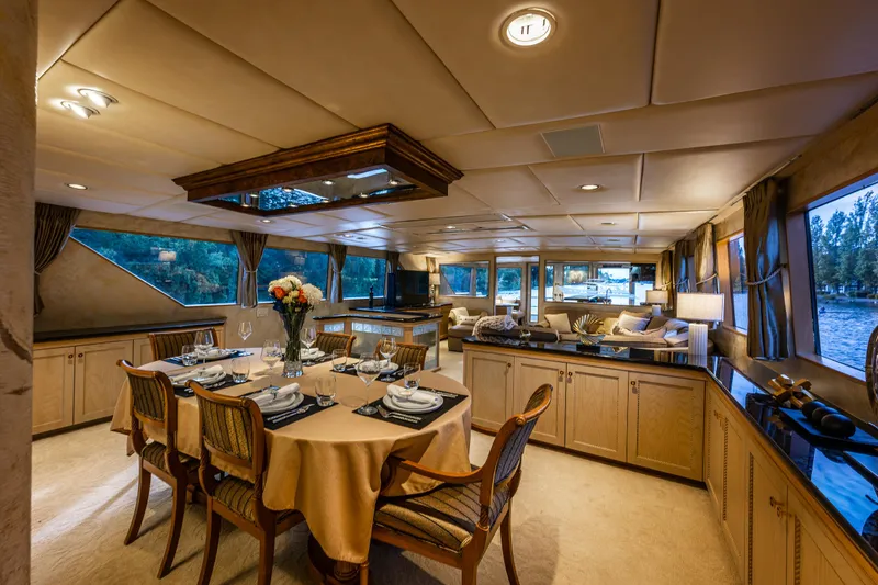 Slide: The Image of Luxurious interior of 1991 Broward 102 yacht with elegant dining area and scenic windows. - 16