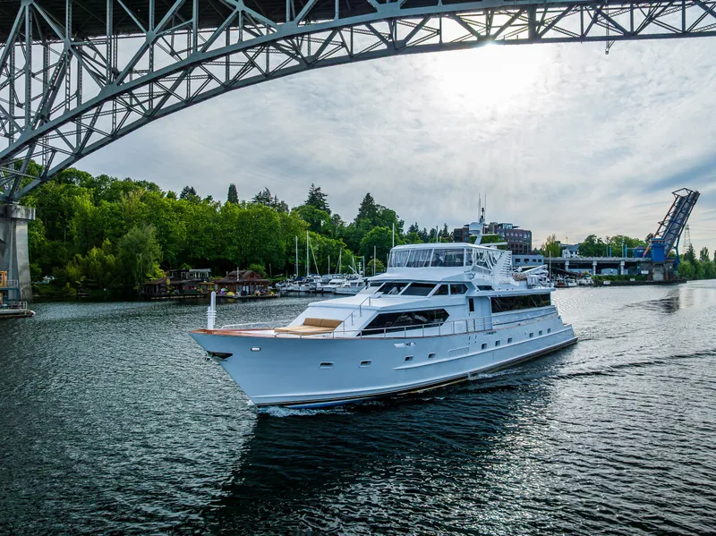 Slide: The Image of Luxury yacht Broward 102 (1991) cruising under a bridge on a scenic waterway. - 2