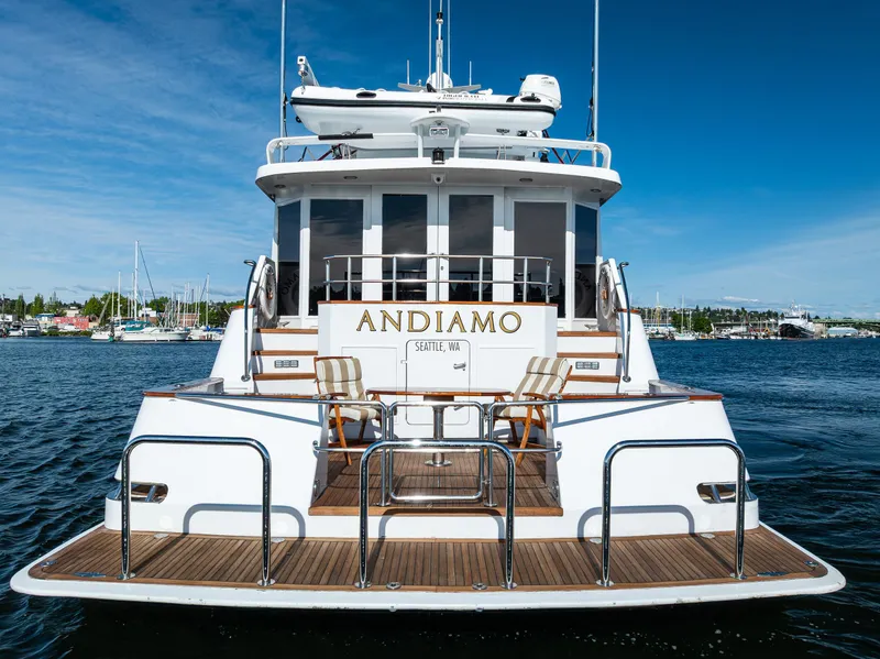 Slide: The Image of Luxury yacht Broward 102, 1991 model, named Andiamo, docked in a scenic marina. - 5