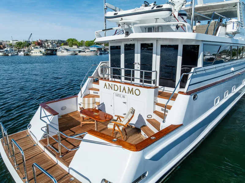Slide: The Image of Luxury Broward 102 yacht from 1991, named Andiamo, docked in a serene marina. - 6