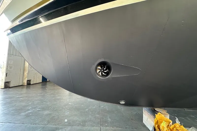 Slide: The Image of Close-up of a 1991 Broward 102 yacht hull with visible thruster in a shipyard. - 91