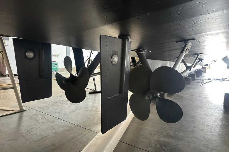 Slide: The Image of Underside view of 1991 Broward 102 yacht showing propellers and rudders in a workshop. - 98