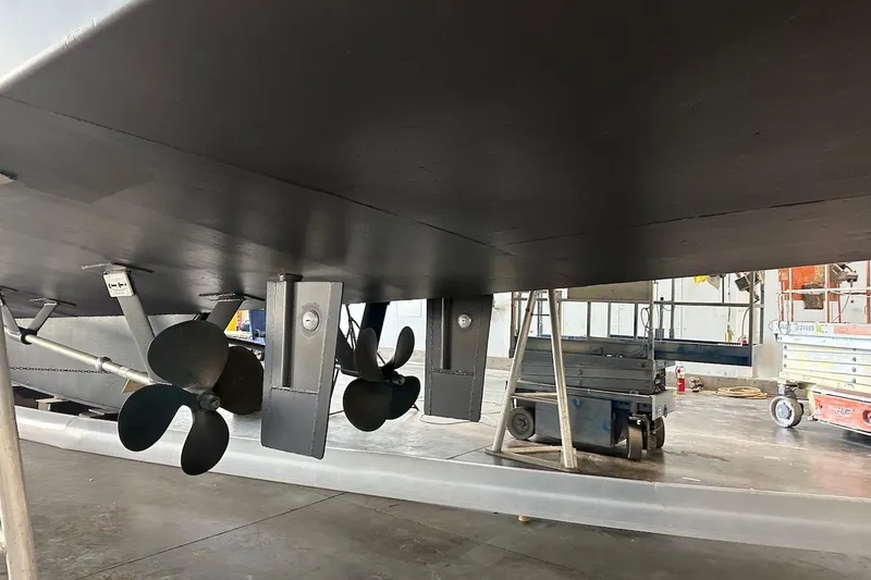 Slide: The Image of Underside view of 1991 Broward 102 yacht with visible propellers in a workshop. - 99