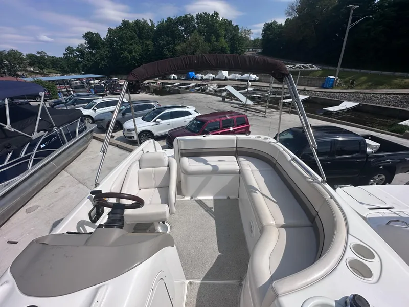 Slide: The Image of 1999 Chaparral 210 Sunesta boat with spacious seating, docked near parked vehicles. - 10