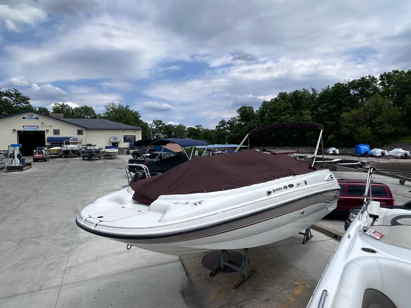 Slide: The Image of 1999 Chaparral 210 Sunesta boat with cover, parked outdoors at a marina. - 5