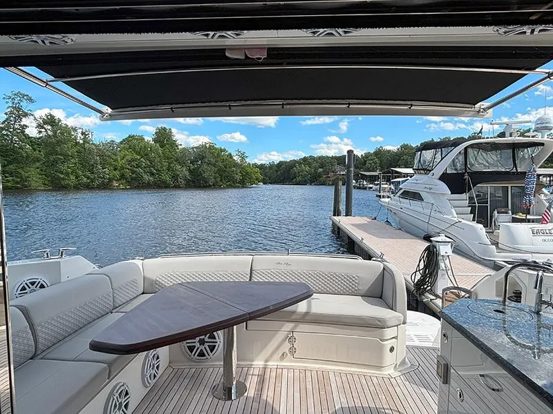 Slide: The Image of 2017 Sea Ray L590 yacht deck with seating, table, and scenic waterfront view. - 20