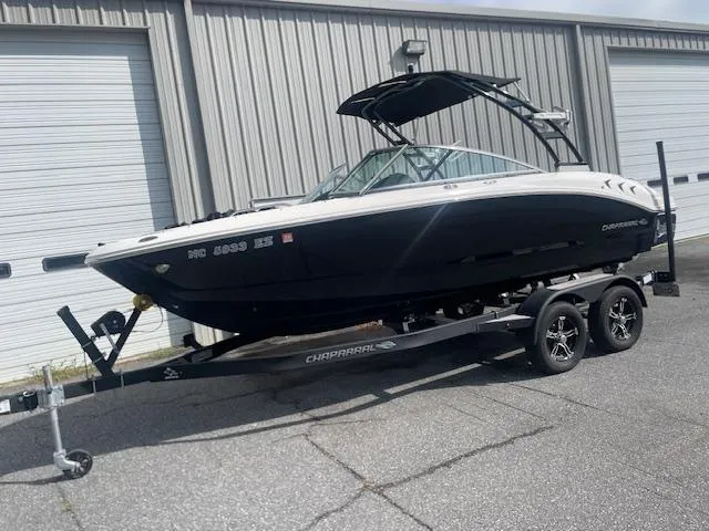 Slide: The Image of 2022 Chaparral 21 Surf boat on trailer, black and white design, parked outside a building. - 3