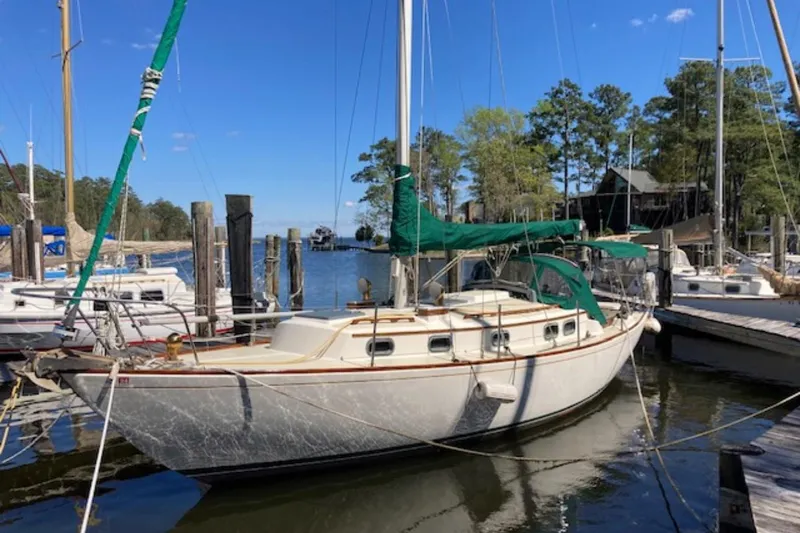 The Image of 1981 Sea Sprite 34 sailboat docked at a marina, surrounded by trees and other boats. - 0