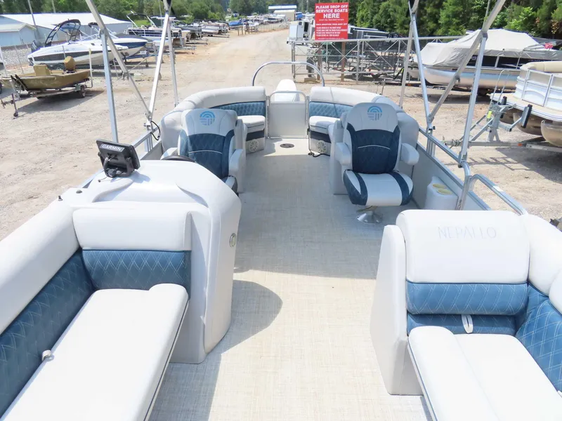 Slide: The Image of 2022 Nepallo pontoon boat interior with blue and white seating, parked in a marina. - 12