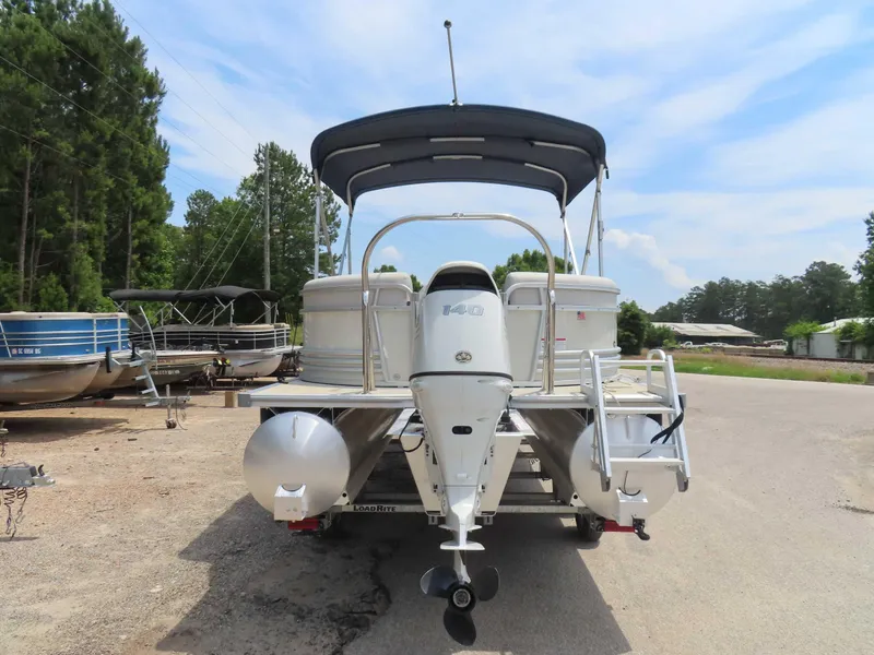 Slide: The Image of 2022 Nepallo pontoon boat with outboard motor, parked on a trailer, surrounded by trees. - 4