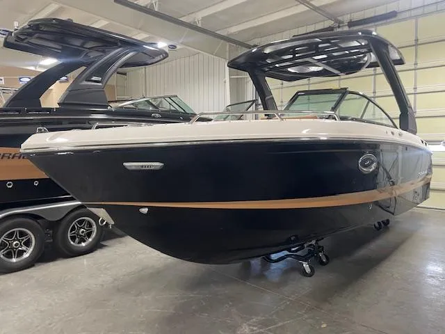 Slide: The Image of 2025 Chaparral 267 SSX boat in showroom, sleek design with black and tan accents. - 2