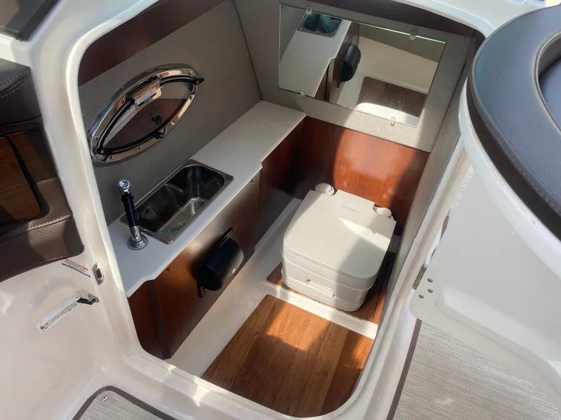 Slide: The Image of 2018 Chaparral 267 SSX boat interior with sink, mirror, and portable toilet. - 16