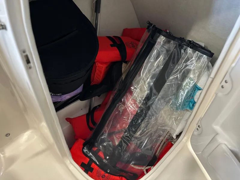 Slide: The Image of Storage compartment in a 2019 Robalo R207 Dual Console with life jackets and gear. - 12